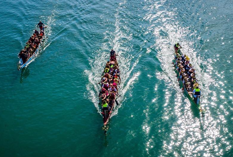 3 dragon boats racing on flat water