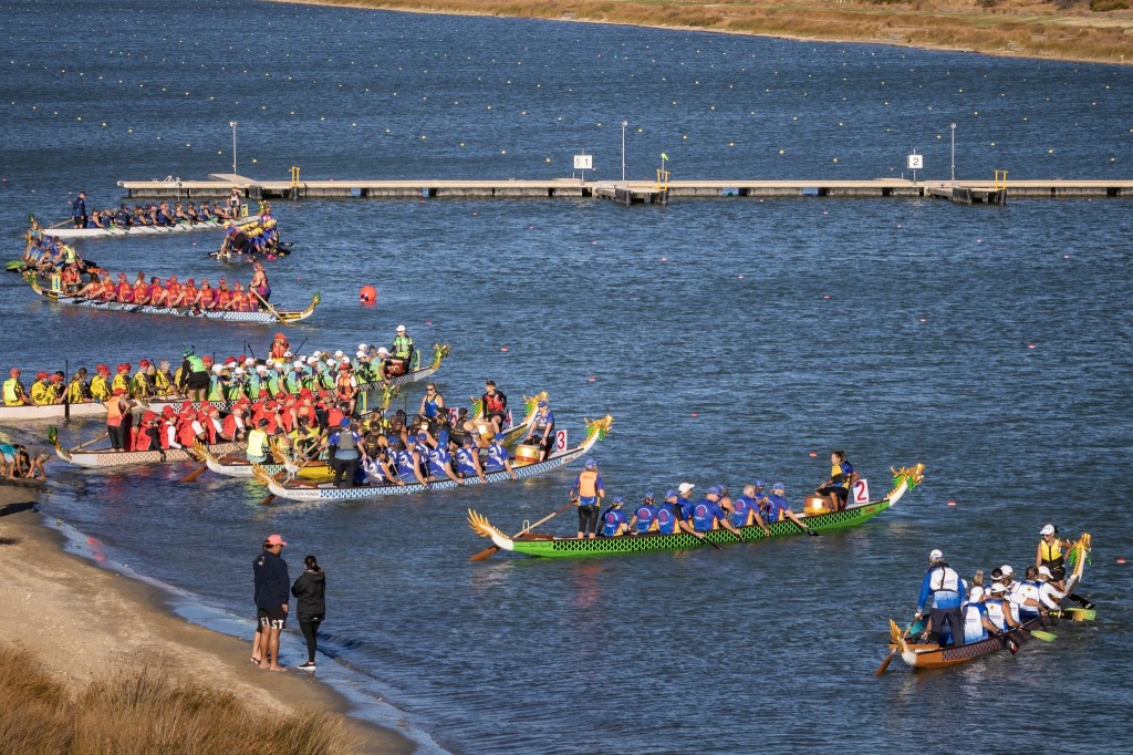 10 dragon boats launching from a beach